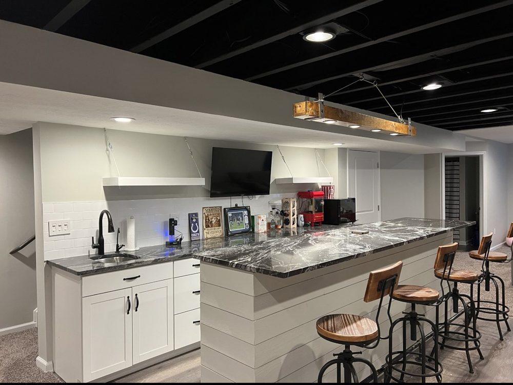 Basement bar with granite counters, stools and a black ceiling