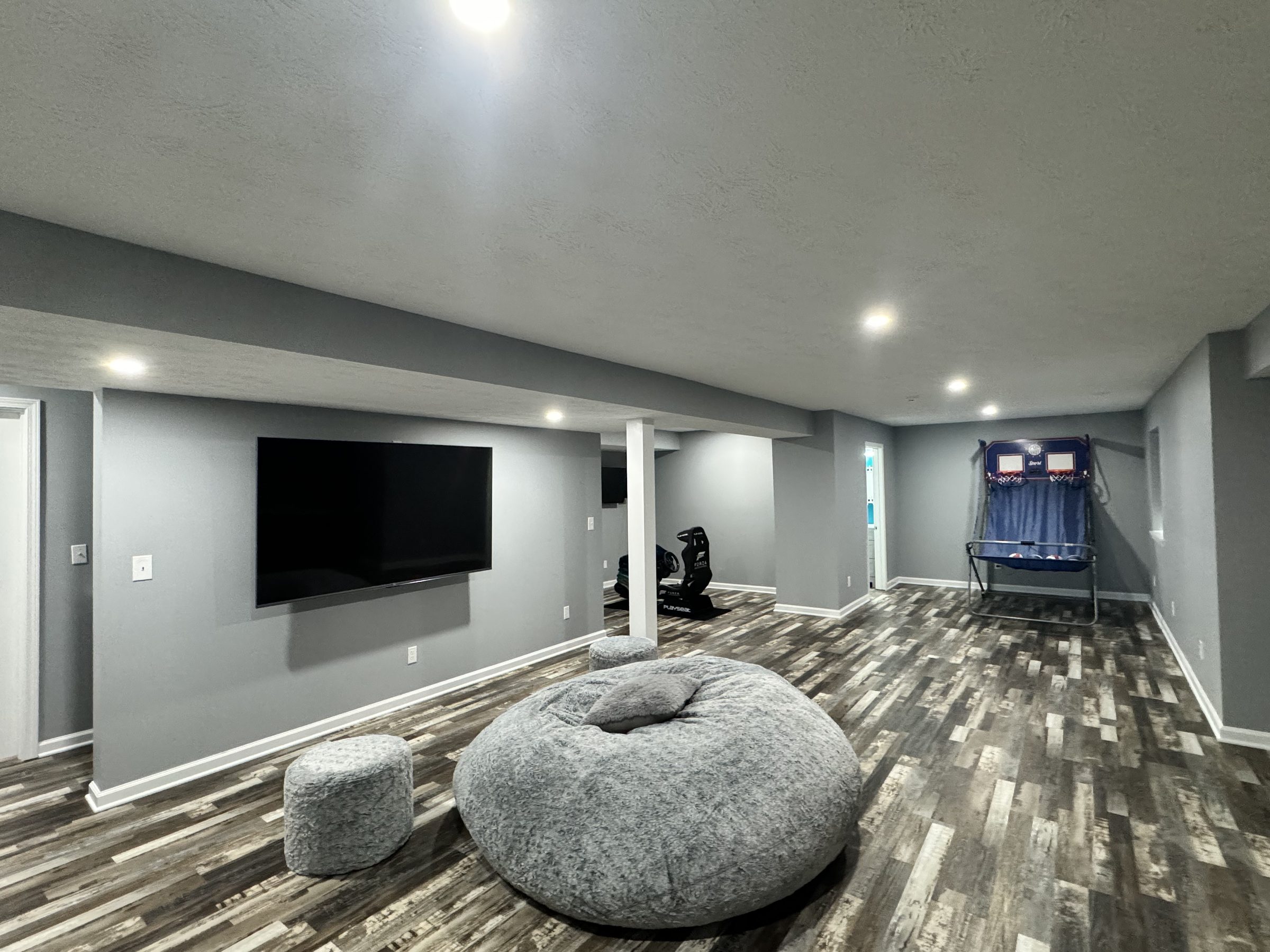 Finished basement living space with a mounted television, wood look flooring and open floor area