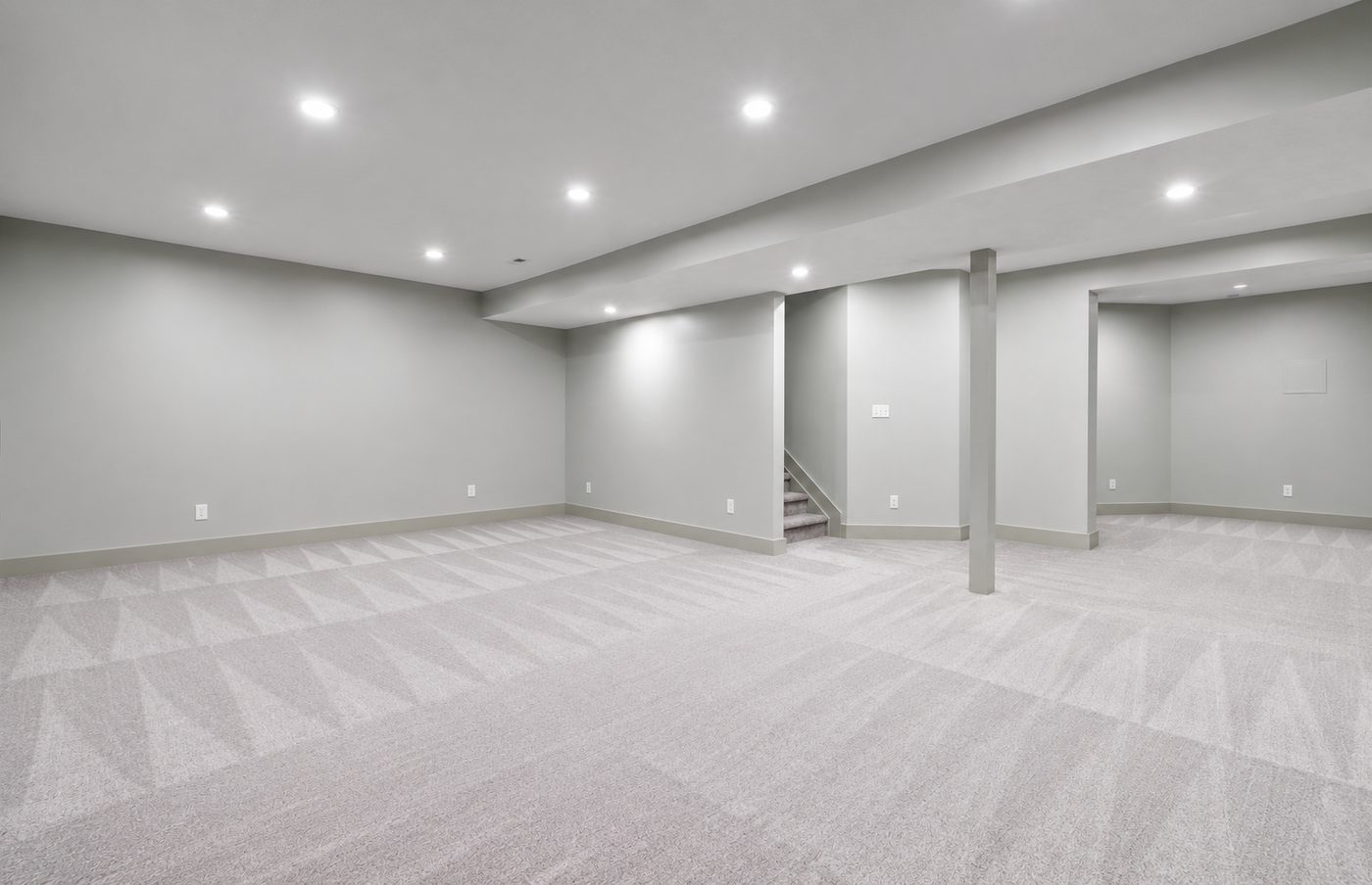 Finished open basement with recessed lighting, new carpet and the stairway landing