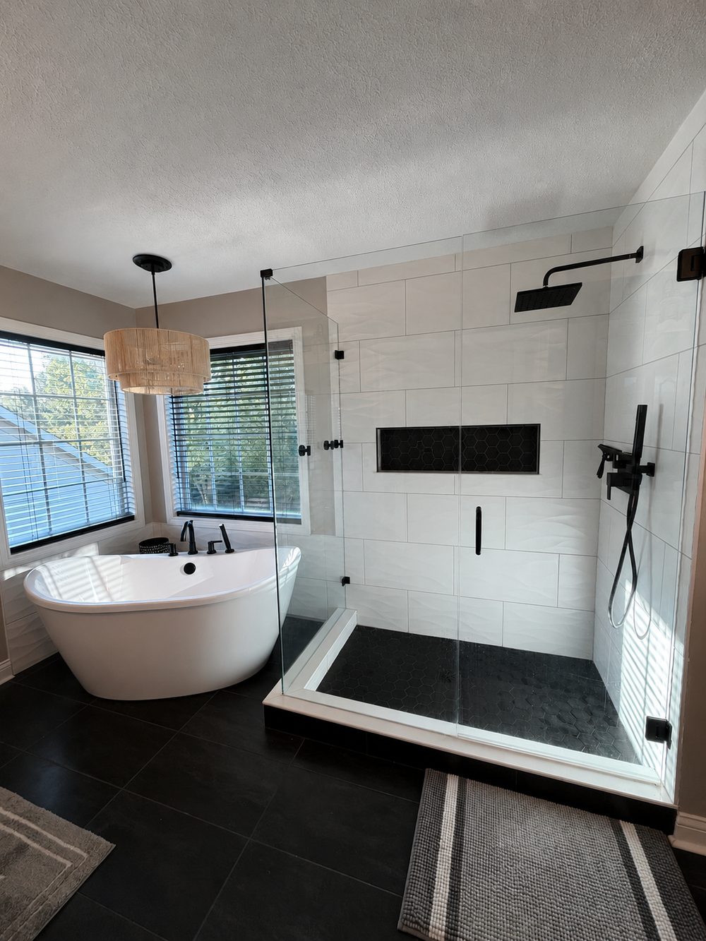 Freestanding tub beside a walk in shower with a glass enclosure and black fixtures
