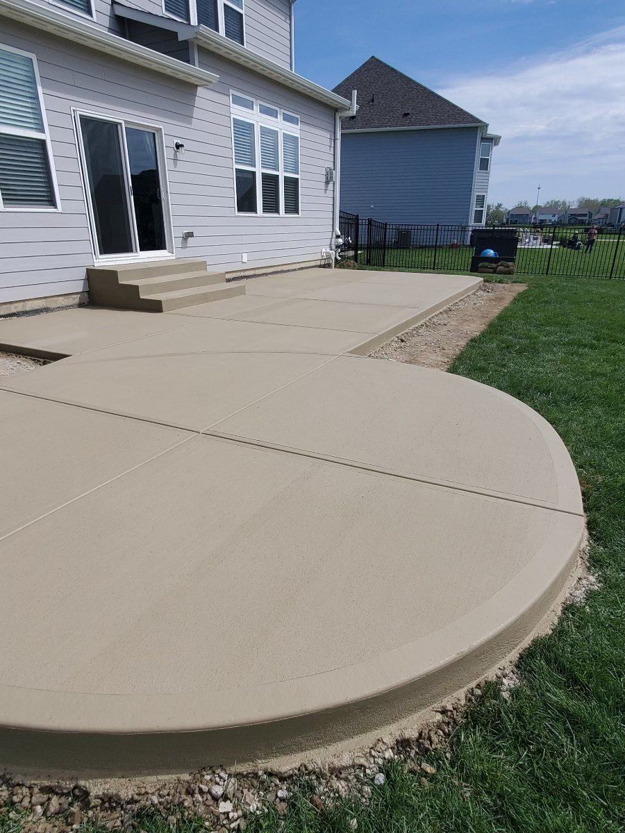 Poured concrete steps from a patio door onto a broom finished concrete patio with a curved edge